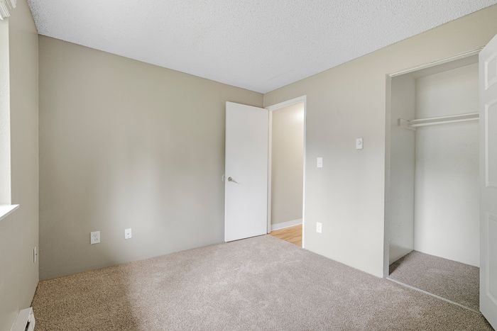 Inviting bedroom with soft carpet, neutral tones, and ample closet space, offering a cozy and serene retreat.