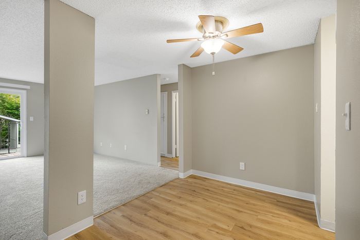Bright and modern apartment interior featuring wood flooring, ceiling fan, and access to a private balcony with natural views.