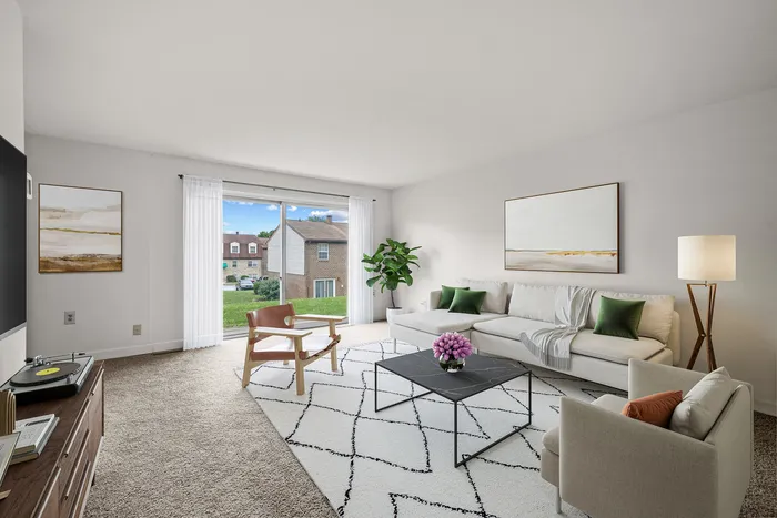 Bright and inviting living room with plush carpet, elegant furniture, and large windows offering a scenic view.