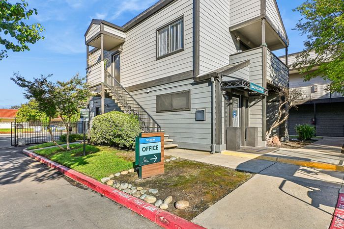 Inviting leasing office exterior with modern wooden siding and lush greenery, providing a welcoming entrance for potential tenants.