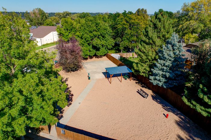 Charming aerial view of a sandy community park area with lush trees, a shaded picnic spot, and a vibrant green landscape&mdash;ideal for outdoor relaxation and recreation.