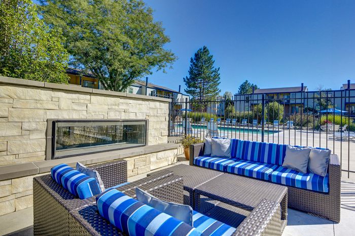 Chic outdoor seating area with stylish blue-striped cushions, perfect for relaxing by the pool under clear skies.