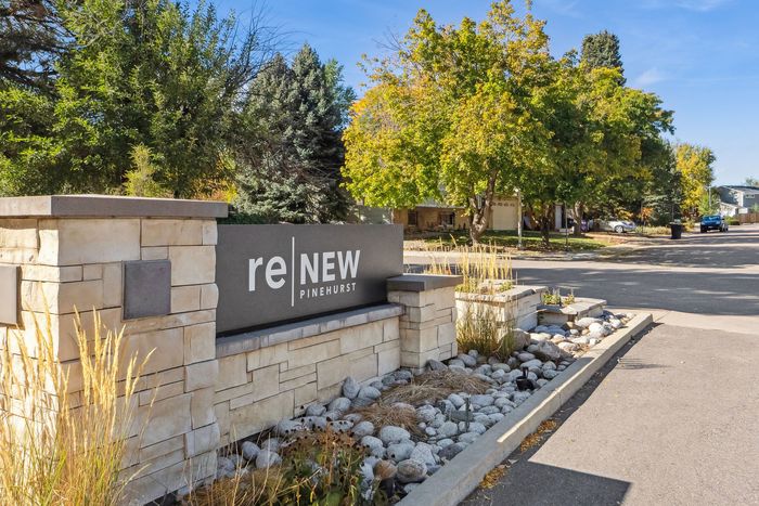Inviting entrance of ReNew Pinehurst, featuring a welcoming stone sign amidst lush greenery and a serene suburban street view.
