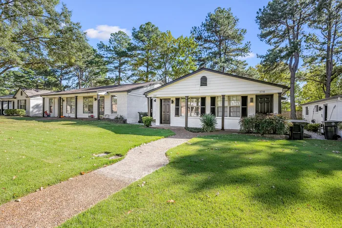 Charming single-story home with a modern exterior and lush green lawn, surrounded by mature trees for a serene living experience.
