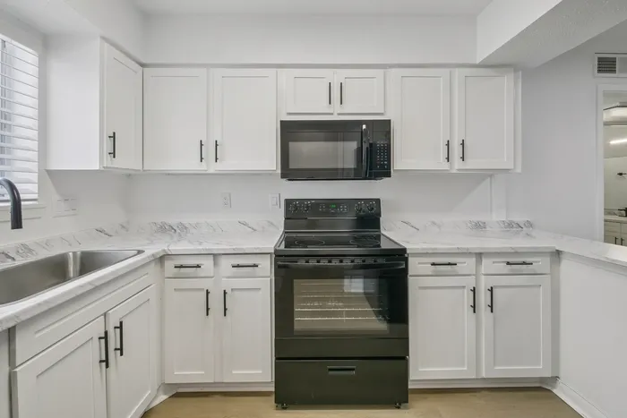 Bright and modern kitchen with sleek white cabinetry, marble countertops, and stainless steel appliances, perfect for home cooking.