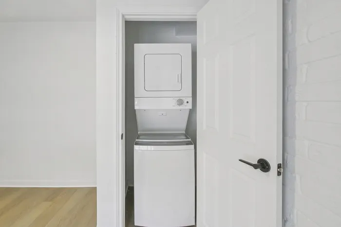 Compact and modern laundry closet featuring a sleek, stackable washer and dryer set, seamlessly integrated into the apartment design.