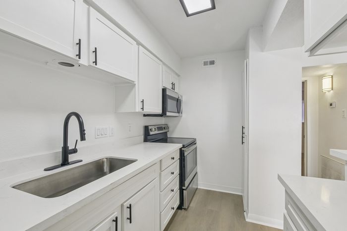 Sleek modern kitchen with stainless steel appliances, white cabinetry, and polished countertops, perfect for culinary enthusiasts.