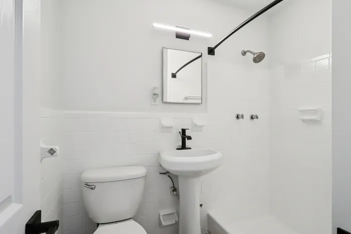 Bright and modern bathroom featuring sleek fixtures, elegant lighting, and a clean white tile design.