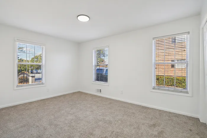 Bright and airy room with plush carpet, large windows, and ample natural light.