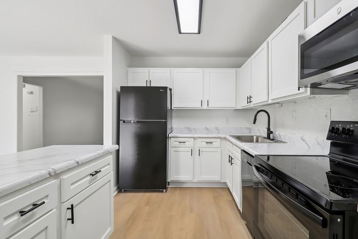 Modern kitchen with elegant white cabinetry, sleek black appliances, and stylish marble countertops.