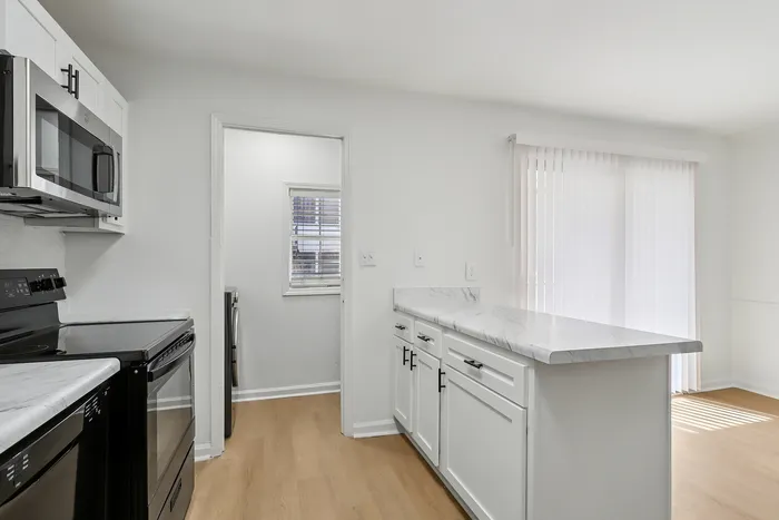 Bright, modern kitchen with sleek black appliances, white cabinetry, and marble countertops.