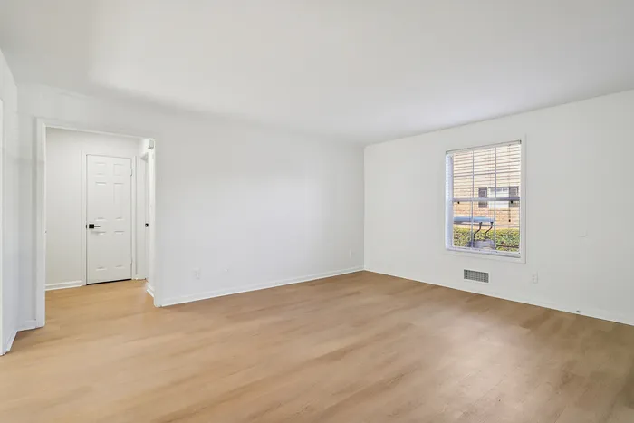Bright, spacious room with elegant wooden flooring and a large window inviting ample natural light.