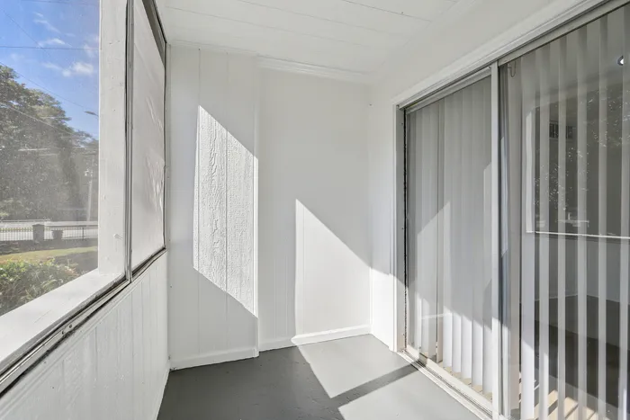 Bright sunroom with large windows and glass sliding doors, ideal for relaxation.
