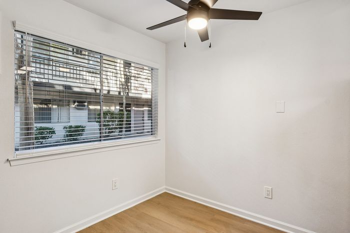 Bright room with large window and modern ceiling fan, offering a cozy and airy ambiance.