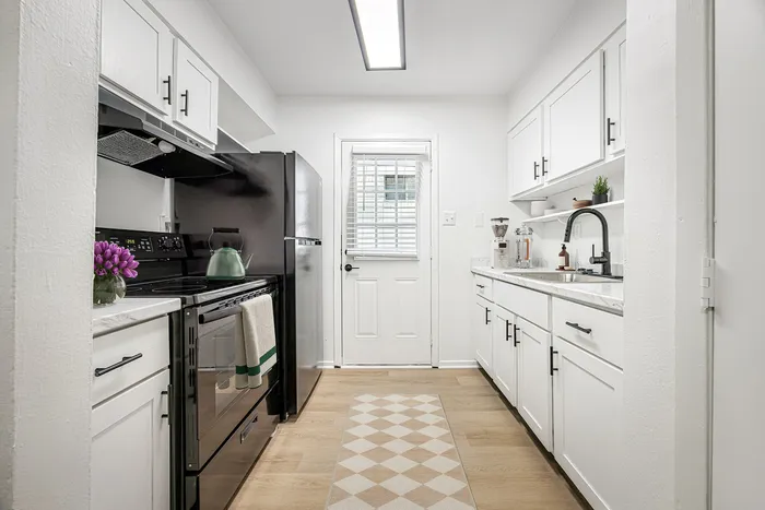 Bright and inviting kitchen with sleek white cabinetry, modern appliances, and a charming wooden floor, offering a perfect blend of style and functionality.
