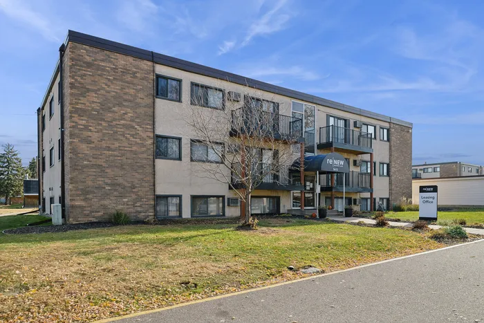 Modern apartment building exterior with balconies and well-maintained landscaping. Leasing office entrance provides easy access.