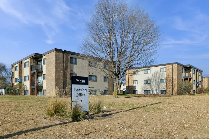 Inviting apartment complex with modern brick facade, spacious grassy surroundings, and a welcoming leasing office at ReNew community.