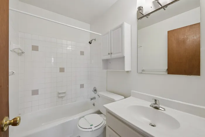 Bright and modern bathroom featuring elegant white cabinetry, a stylish mirror, and a classic shower-tub combination.
