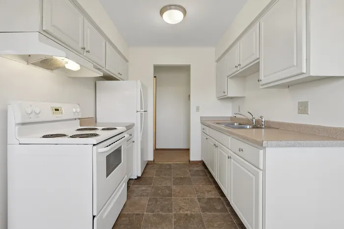 Bright, modern kitchen with clean white cabinetry, sleek countertops, and essential appliances, ideal for culinary enthusiasts.