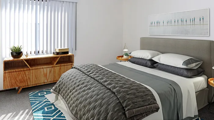 Bright and inviting bedroom featuring a plush gray bedspread, stylish wooden dresser, and modern artwork in a cozy ambiance.