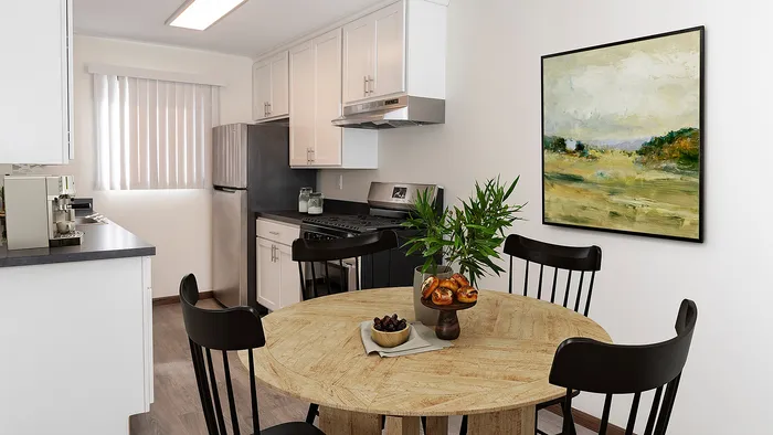 Bright, modern kitchen with sleek white cabinets, stainless steel appliances, and a cozy dining area featuring a wooden round table.