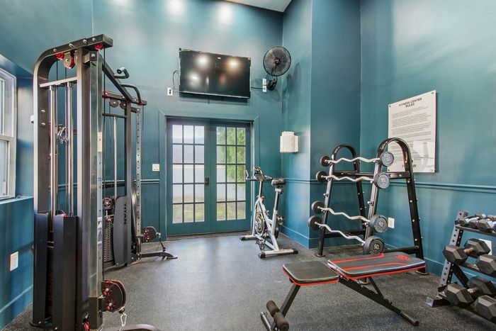 Modern fitness center featuring state-of-the-art gym equipment, vibrant teal walls, and ample natural light.