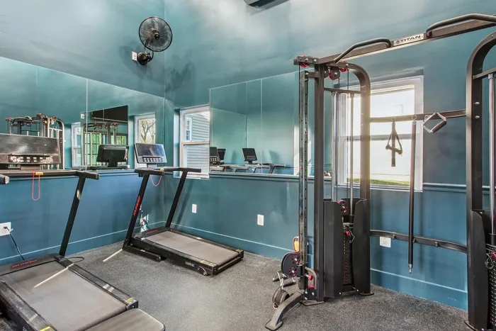 Modern fitness room with sleek treadmills and a versatile gym station against a stylish blue wall, reflecting an inviting exercise space.