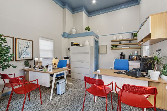 Chic home office with vibrant red chairs, stylish desks, and lush indoor plants, creating a modern, inviting workspace.