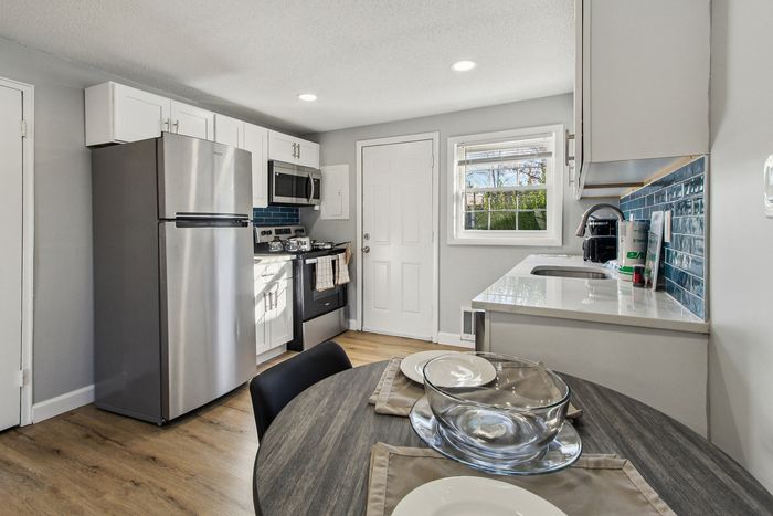 Bright and inviting modern kitchen with stainless steel appliances, chic white cabinetry, and a cozy dining area.