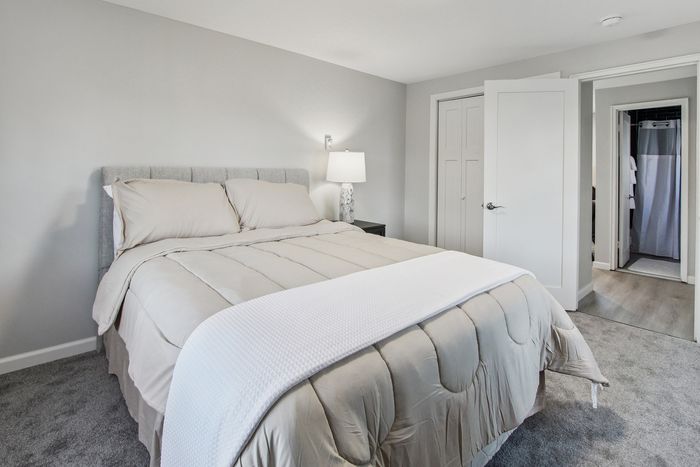 Bright and inviting bedroom with a plush bed, elegant bedding, and soft lighting, perfect for relaxation.