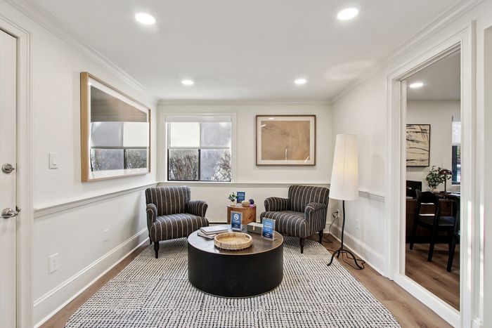 Cozy living area with elegant striped armchairs, a modern round coffee table, and soft ambient lighting, perfect for relaxation.