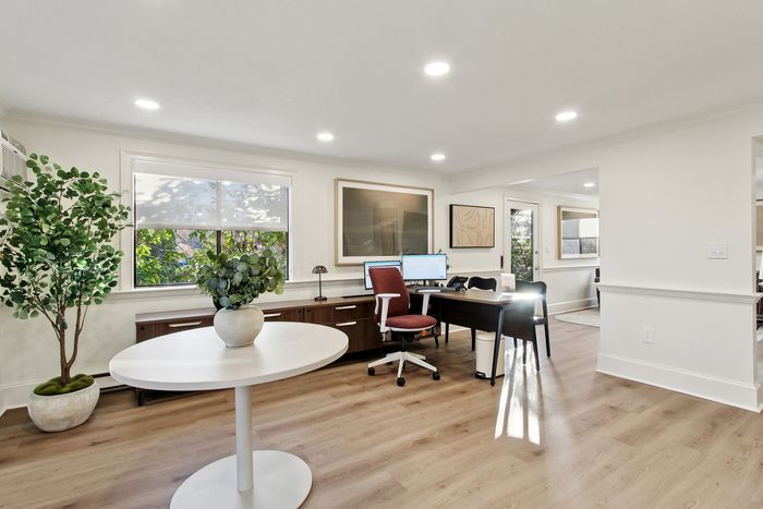 Bright home office with chic decor, large window, and sleek furnishings creating a productive yet serene workspace.