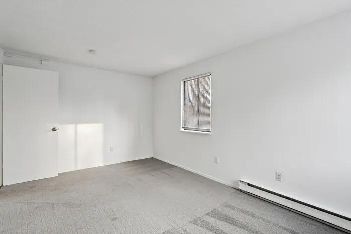 Bright, spacious room with neutral walls and a large window perfect for natural light, ideal for a cozy bedroom or home office setup.
