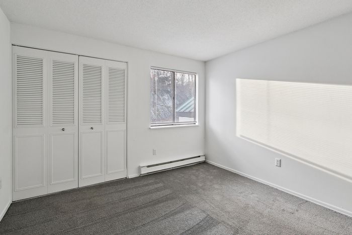 Bright, airy bedroom featuring soft carpet flooring, large closet space, and natural light streaming through a window, creating a cozy and inviting atmosphere.