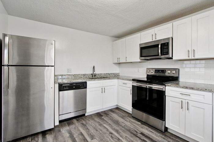 Modern kitchen with sleek stainless steel appliances, elegant granite countertops, and stylish white cabinetry.