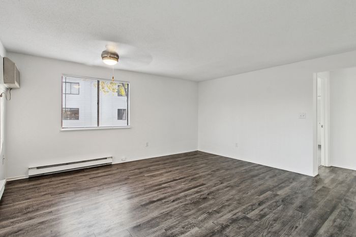 Bright and airy living room with sleek hardwood floors and a modern ceiling fan, perfect for contemporary living.