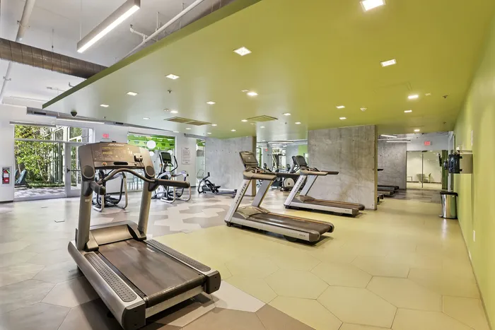 Modern fitness center with state-of-the-art treadmills, sleek design, and vibrant green accents, offering a dynamic workout environment.