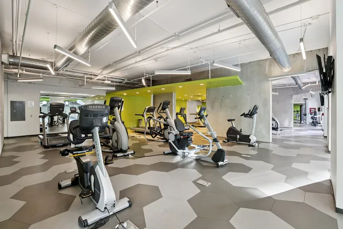 Contemporary gym with state-of-the-art equipment, vibrant green accents, and modern geometric flooring, perfect for a premium workout experience.