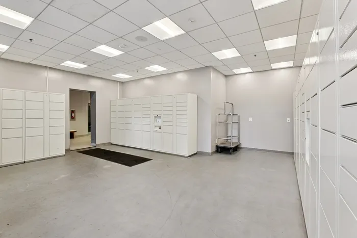 Modern package locker room with sleek white lockers and bright overhead lighting, ensuring secure and organized delivery management.