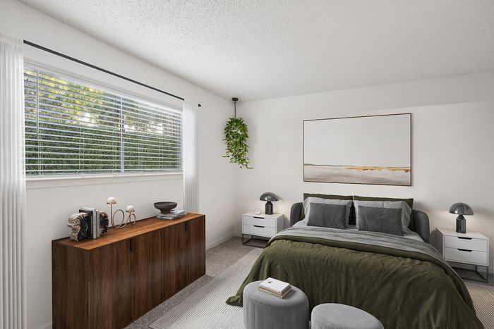 Bright and inviting bedroom with a large window, stylish decor, and plush bedding in neutral tones.