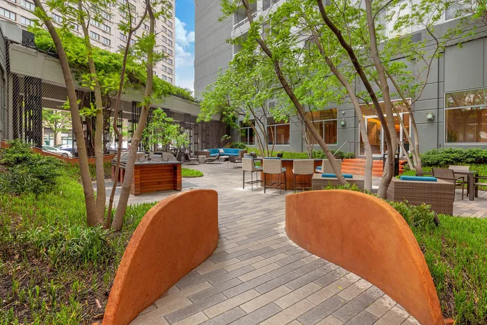 Inviting courtyard with lush greenery, modern seating, and a cozy outdoor dining area, perfect for relaxation and gatherings.