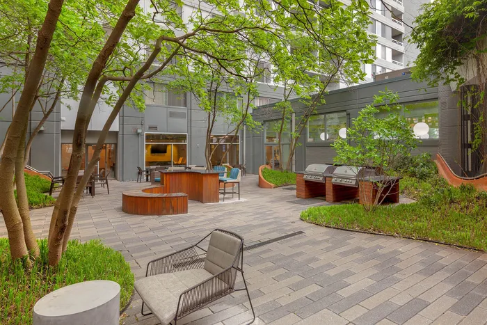Inviting outdoor patio with lush greenery, modern grill stations, and comfortable seating, perfect for entertaining.