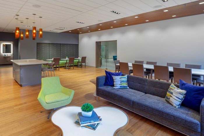 Modern open-concept lounge with a cozy sofa, vibrant green chair, sleek dining area, and stylish pendant lighting.