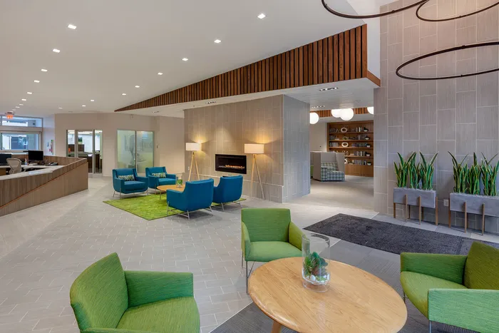 Modern, inviting lounge area with stylish green and blue seating, contemporary fireplace, and accent lighting, perfect for relaxation and networking.
