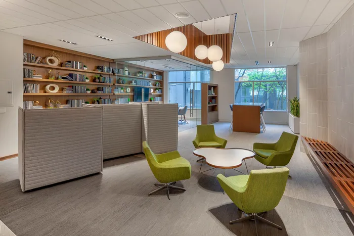 Modern communal space with vibrant green chairs, elegant shelving, and natural lighting.