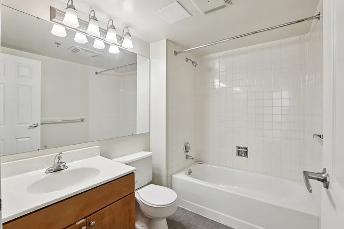 Bright and modern bathroom with sleek fixtures, a full bathtub, and a spacious vanity mirror.