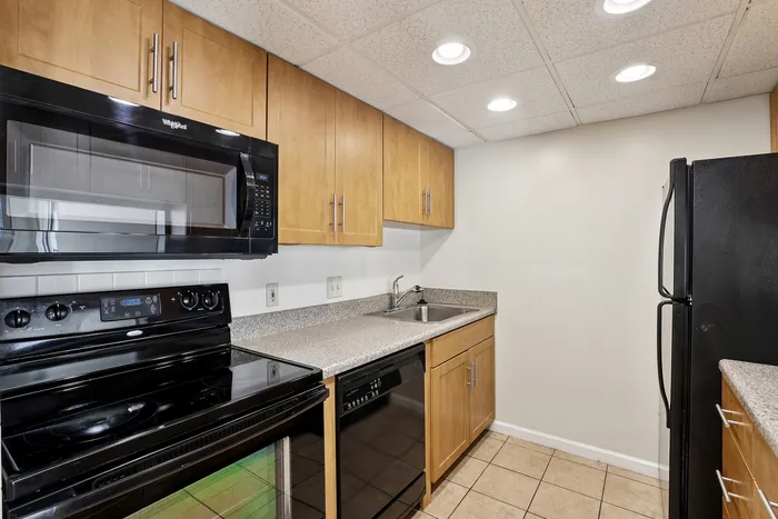 Modern kitchen with sleek black appliances, wood cabinets, and granite countertops, offering a blend of style and functionality.