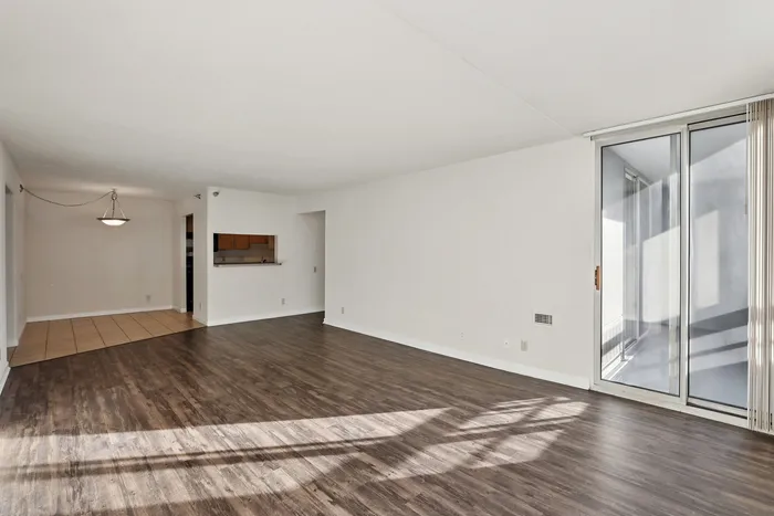 Bright open living space with elegant hardwood flooring, large sliding glass doors, and a modern chandelier.