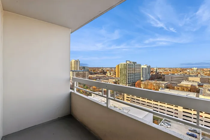 Charming balcony view showcasing a vibrant cityscape under a bright blue sky, perfect for relaxation and urban living.