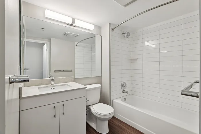 Elegant bathroom with modern fixtures, featuring a sleek countertop, spacious mirror, and polished tile bathtub.